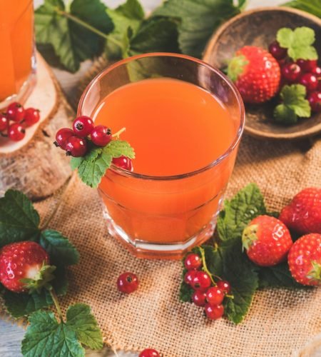 A refreshing glass of berry juice surrounded by fresh strawberries and red currants. Perfect for a healthy lifestyle.